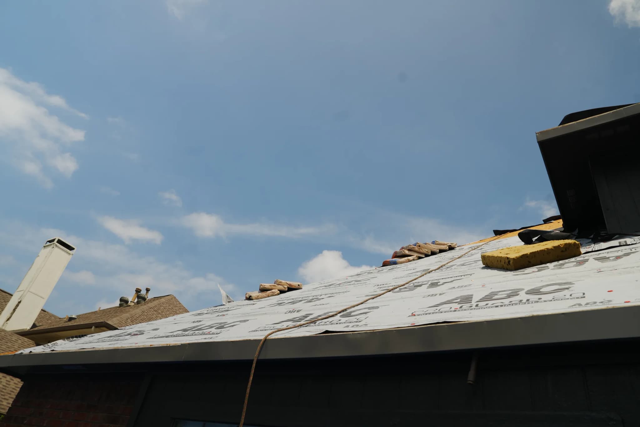 Low-angle view of JRH residential roof job showing ABC underlayment + ridge prep in Allen TX